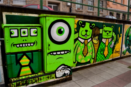 Fotografía de una caja de contadores eléctricos decorada con el grafiti de unos monstruitos de color verde